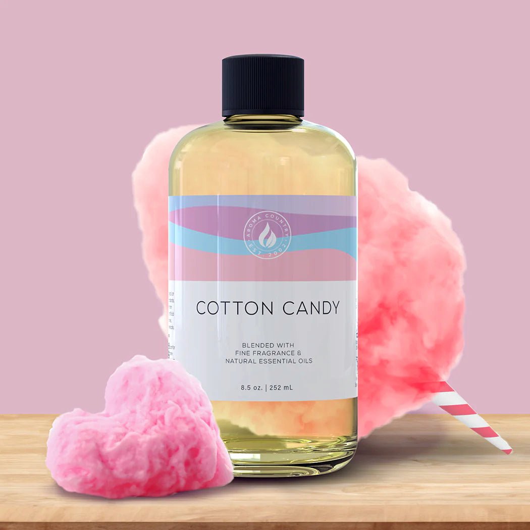Cotton Candy diffuser oil in an 8.5 oz bottle, surrounded by fluffy pink cotton candy and a heart-shaped tuft, evoking playful, sugary aromas.