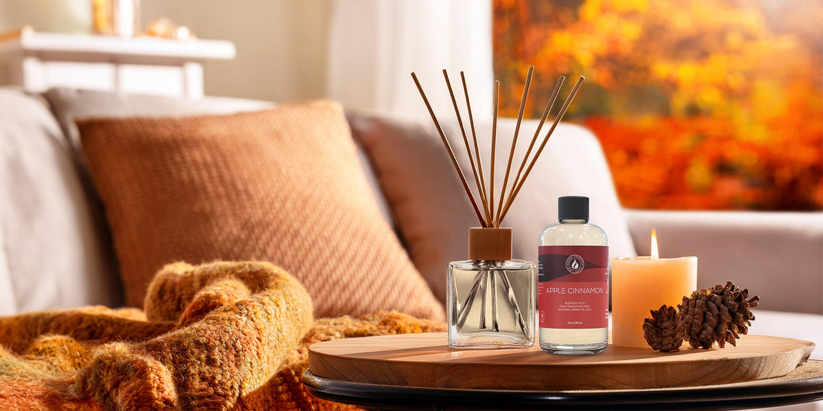 Aroma Country Apple Cinnamon diffuser oil staged in a warm, cozy living room with fall décor, candlelight, and pinecones for a seasonal home scent atmosphere.