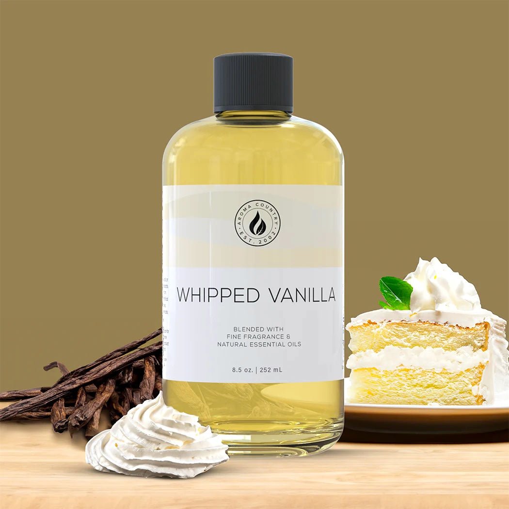 Whipped Vanilla diffuser oil in an 8.5 oz bottle with creamy dessert accents, vanilla beans, and a slice of frosted cake for a warm and sweet fragrance profile.